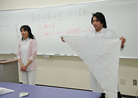 応急処置に役立つ三角巾の説明をする川畑先生と森先生